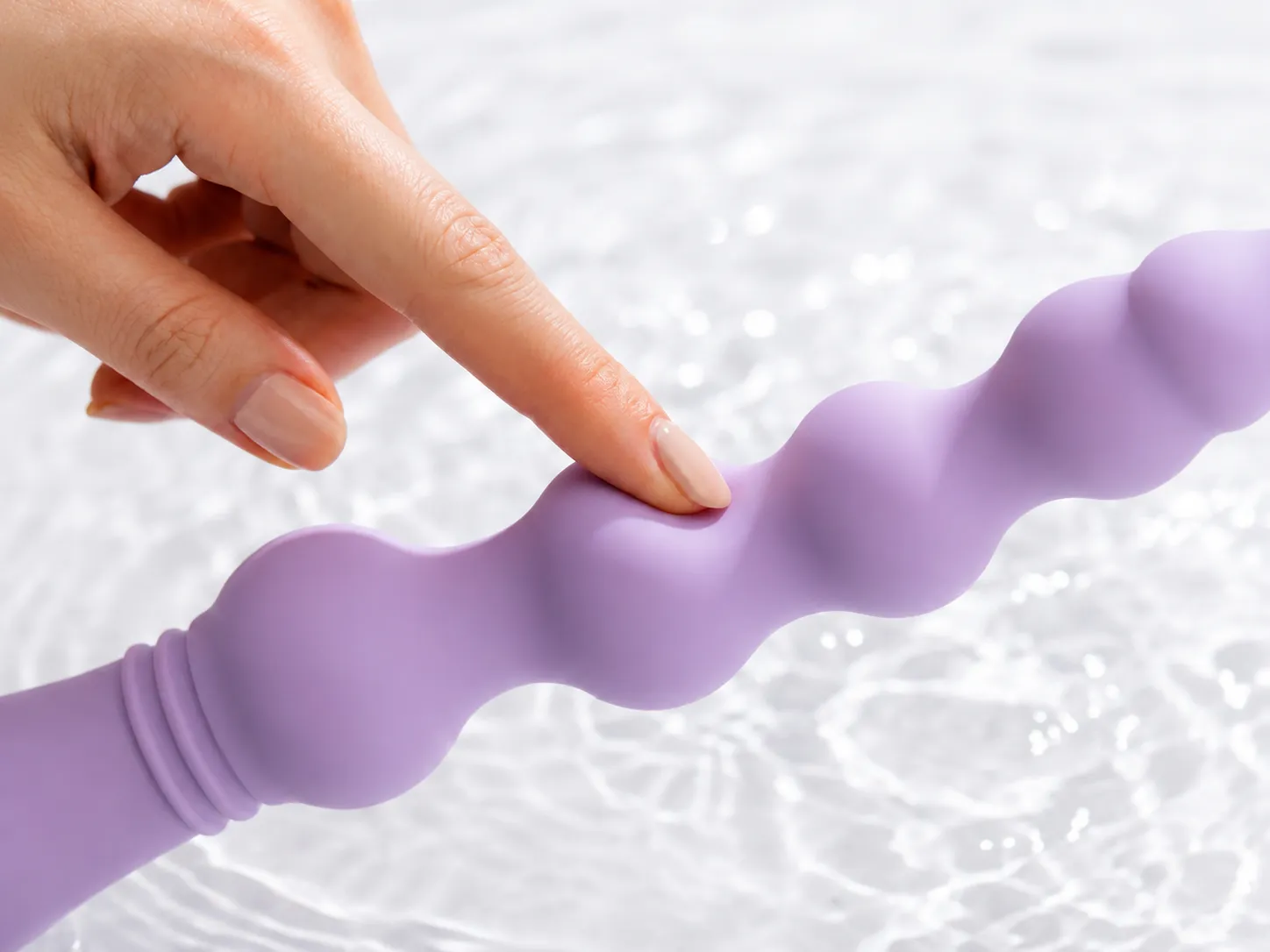 Fingertip pressing into the soft lavender silicone bead of the CoreSeal Cascade beaded anal vibrator