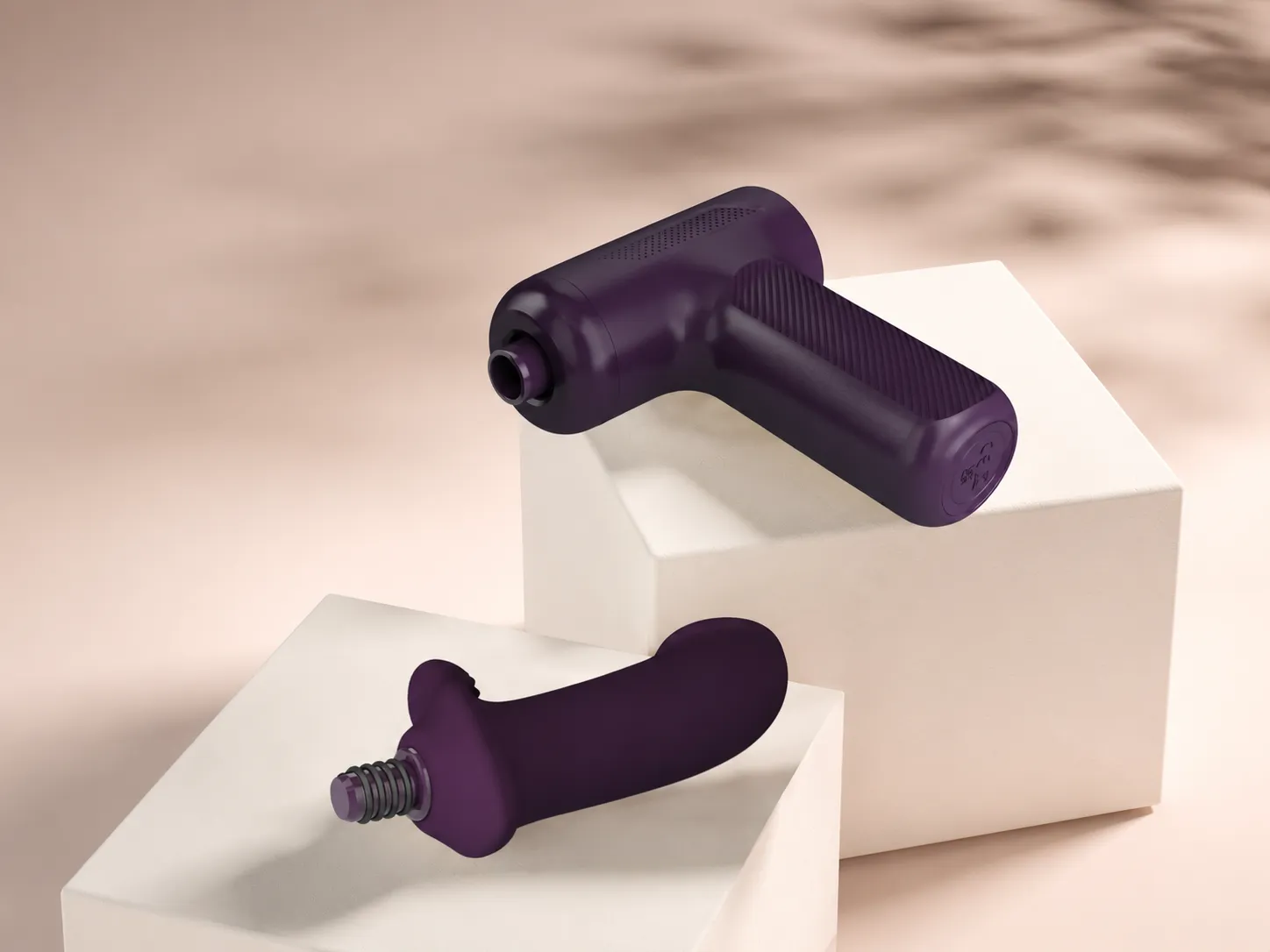 Silicone attachment head detached from a deep plum massage gun handle, showing the screw-on threaded connector