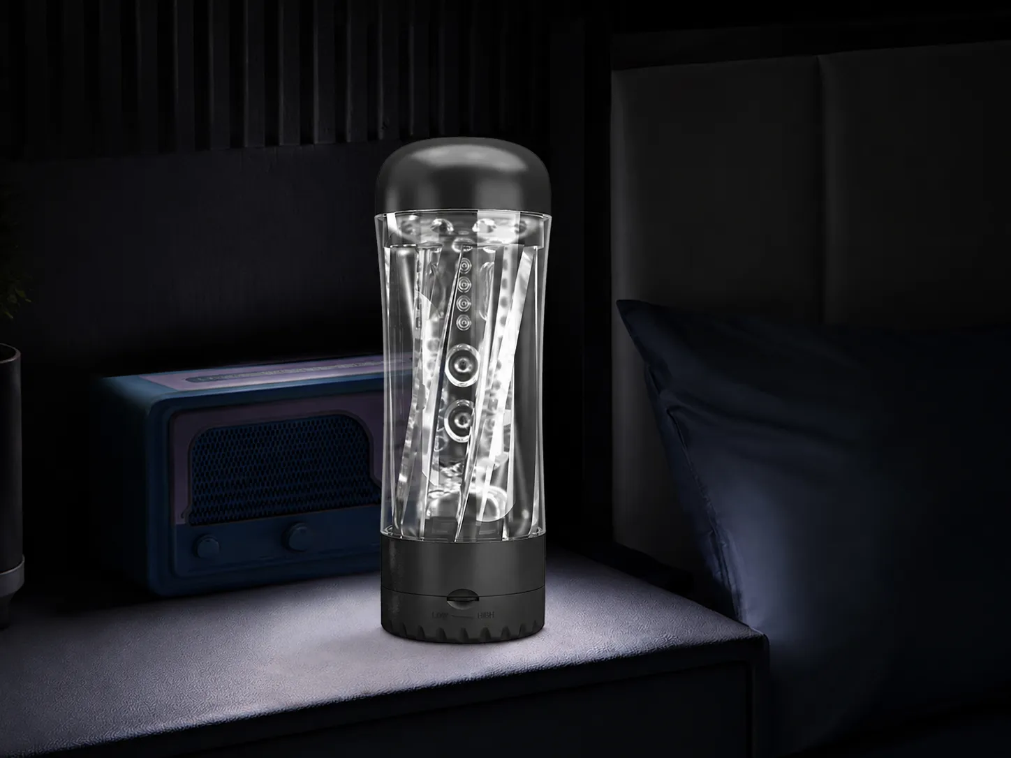 Clear vibrating masturbator cup standing on a bedside table in a dim bedroom